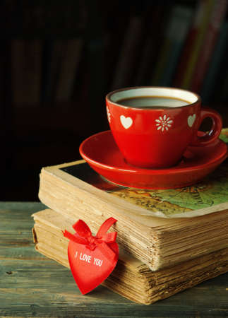 Valentine's card with old vintage books and cup of coffee on a wooden tableの写真素材