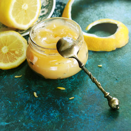 Homemade lemon curd in glass jar, with fresh lemons (toned picture)の写真素材