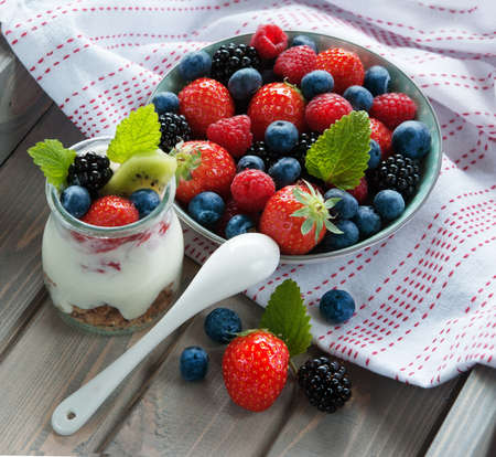 Healthy breakfast, muesli with fresh blueberry, blackberry, raspberries, strawberry, kiwi, mint and yogurtの写真素材