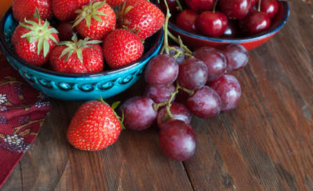 Summer berries in bowls and grapes  on wooden table, fruits, cherry, strawberryの写真素材