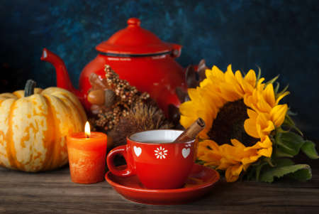 Cup of tea and Autumn thanksgiving decor with candle, sunflower and pumpkinの写真素材