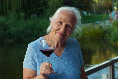 Happy Elderly woman drinking red wine, outdoorsの写真素材
