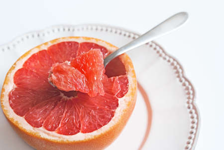Piece of pink grapefruit in a tea-spoon, healthy citrus dessertの写真素材