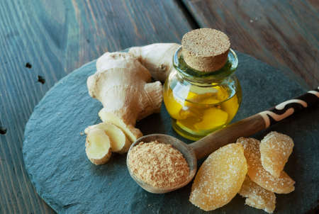Fresh ginger root, ginger spice powder, oil, honey and slices of candied ginger on wooden backgroundの写真素材