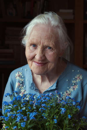 Portrait of the smiling elderly woman with flowers, mother day