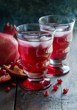 Pomegranate juice in glass and seeds on the wooden tableの写真素材