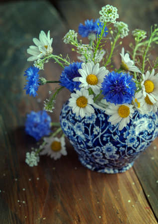 Camomile and cornflowers in a pitcher on table. Flowers from the fieldの写真素材