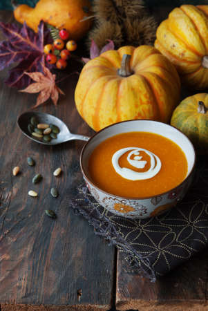 Autumn pumpkin soup with seeds on a wood tableの写真素材