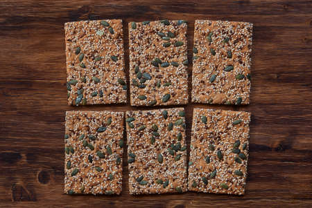 Crunchy crispbread  on a wooden background. Healthy snack: cereal crunchy multigrain cereal flax seed pumpkin, coriander, sesame, sunflower seeds protein bread bar. Protein albumin source.の写真素材