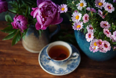 Beautiful flowers in vase and cup of tea at wooden table. Selective focusの写真素材