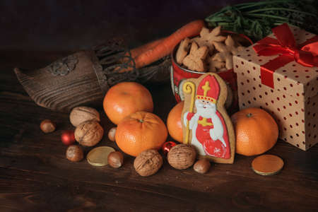 Holiday background Saint Nicholas, Sinterklaas, with traditional dutch shoe with carrots, cookies, nut, tangerines, gifts and sweetsの写真素材