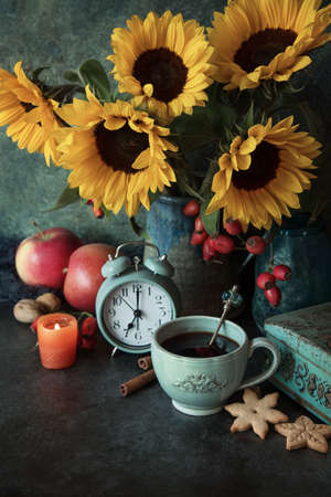 Beautiful flowers and cup of coffee with cookies , autumn decor with apples, candle and alarm clockの写真素材