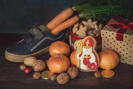 Holiday background Saint Nicholas, Sinterklaas, with children shoe with carrots, cookies, nut, tangerines, gifts and sweetsの写真素材