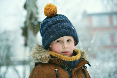 Thinking little boy outdoor at snowfall winterの写真素材