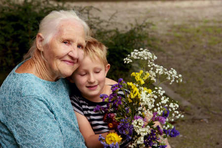 Outdoor portrait of Elderly woman with her grandson in the park