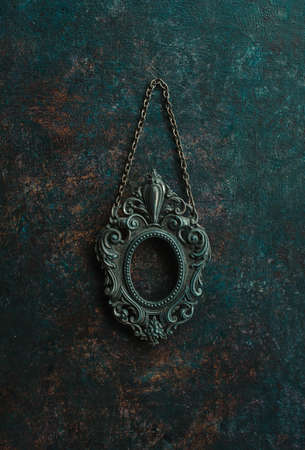 Vintage openwork bronze metal oval frame on a old wall backgroundの写真素材