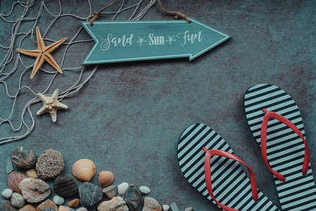 Beach background. Top view of beach seashells, starfish, shells, flip flops and sea pebbles on blue wooden background. Summer concept, arrow with a slogan, Vintage retro styleの写真素材