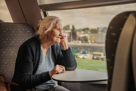 Elderly woman looking in window, traveling by train in Europeの写真素材
