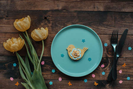 Easter table setting background with flowers. Plate with easter decor on the wooden tableの写真素材