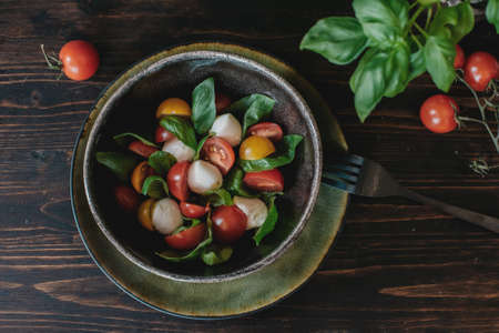 Tasty caprese salad with ripe red tomatoes, mozzarella, and basil. Italian food. Top view