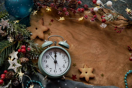 Christmas decorations and alarm clock at wooden desk with place for text