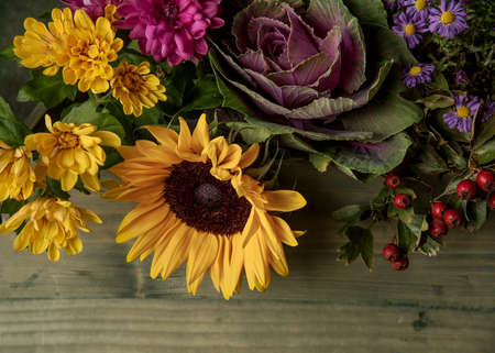 Beautiful autumn flowers and berries on the green wooden background. Top view with copy space. Autumnal concept.の写真素材