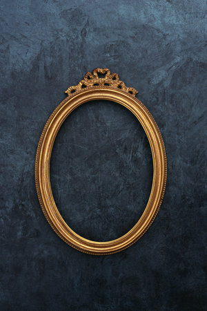 Vintage openwork gold oval frame on a old wall backgroundの写真素材