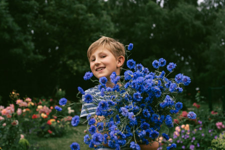Happy blond boy in the garden with a bouquet of flowers cornflowersの写真素材