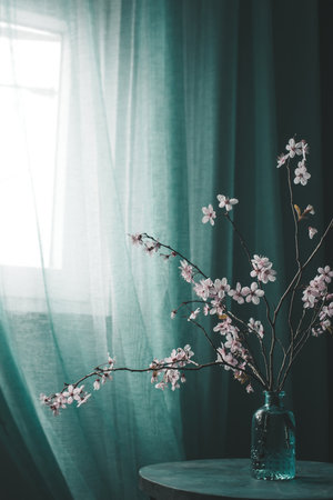 Branch of cherry blossom in a vase on a table in the interior in springの写真素材