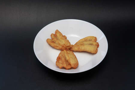 Three fried bananas are served on a white plate. These snacks are found in Indonesia, Singapore and Malaysia.の写真素材