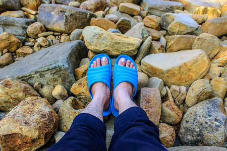 A pair of feet wearing blue footwear on the rock.の写真素材