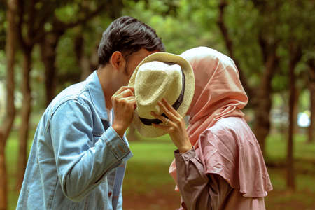 Couples whispering or kissing under cowboy hats.の写真素材