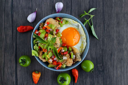 Rice in a bowl filled with beef eye eggs and chopped fried fish smothered in very hot chili sauce....