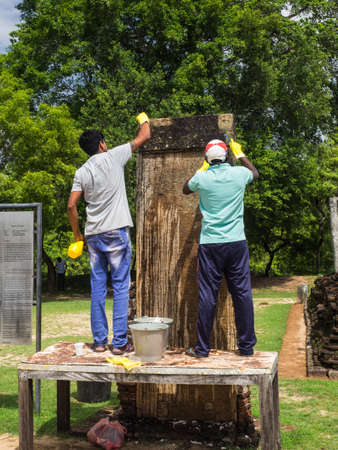 Pollannaruva, Sri Lanka - November 9, 2017: The unidentified workers cleaning the 12th century stone inscriptions in the archaeological park.のeditorial素材