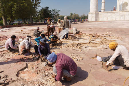 Agra India - March 11, 2018: Workers manually repairing the outside ground of Taj Mahal, the famous ivory-white marble mausoleum in Agra, India.のeditorial素材