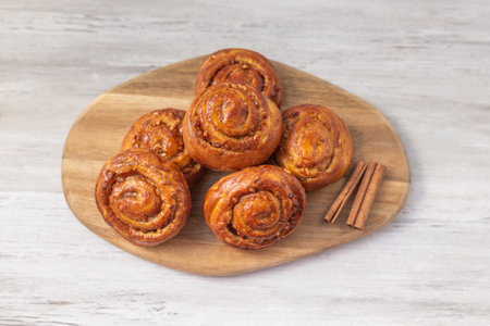 Sweet rolls with cinnamon on wooden board. Caramel buns with nuts. Tasty dessert.の写真素材