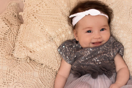 Portrait of adorable smiling newborn baby with thick brown hair. Nude newborn child relaxing in bed....