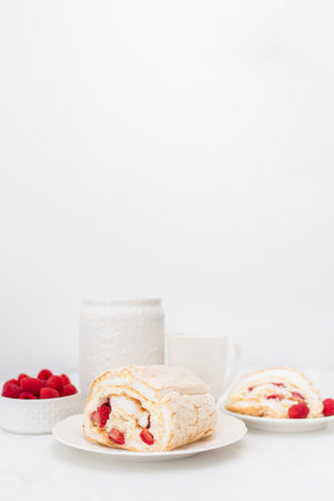 Meringue roll with strawberries and raspberries on white wooden table. Homemade cake.の写真素材