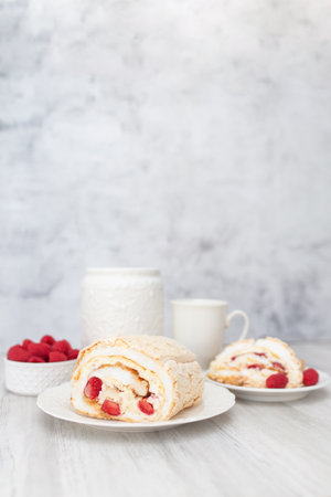 Meringue roll with strawberries and raspberries on white wooden table. Homemade cake.の写真素材
