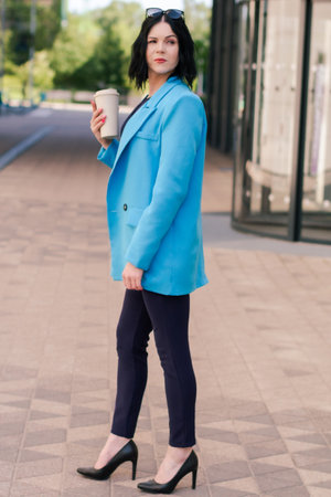 Young elegant Asian professional business woman, lady executive manager wearing suit holding coffee cup standing outdoor during work break.の写真素材