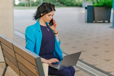 Young business woman leader entrepreneur, professional manager with coffee holding laptop computer on the street in city on buildings background.の写真素材