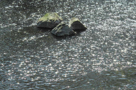 Stones in a River With Sunlight Reflecting on the Rippled Water - River Taff, Cardiff, Walesの写真素材