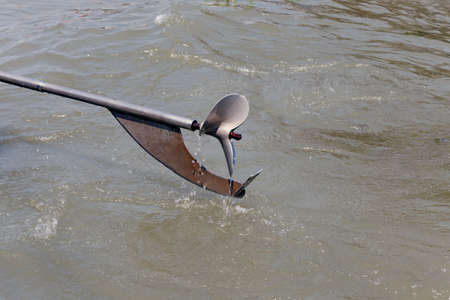 The long propeller tail of the little boat.