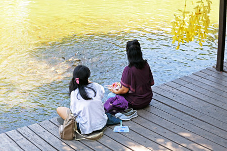 Ratchaburi / Thailand - April 21 2018:Thai people feeding fish at the river in public park.のeditorial素材