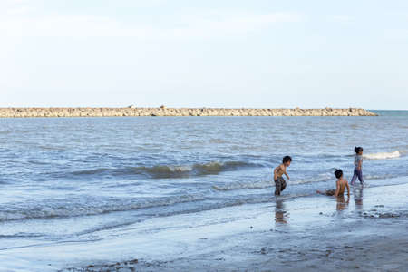 young boy playing in the sand and waves on the beachの写真素材