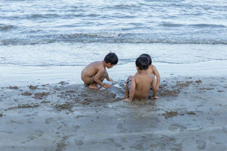 young boy playing in the sand and waves on the beachの写真素材
