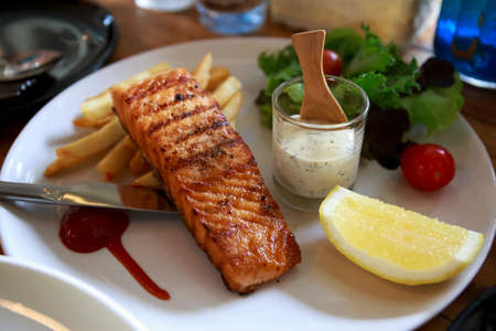 sALMON GRILL WITH cream sauce and french fries.
