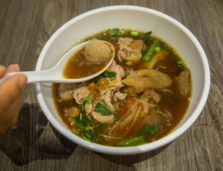 Close up Beef noodle soup in white bowl served on the table.