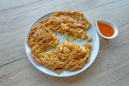Crab omelet with chili sauce on wooden table