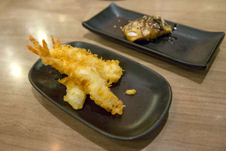 Tempura fried shrimp in black plate on the wood table (Japanese style), in focus selective.の写真素材